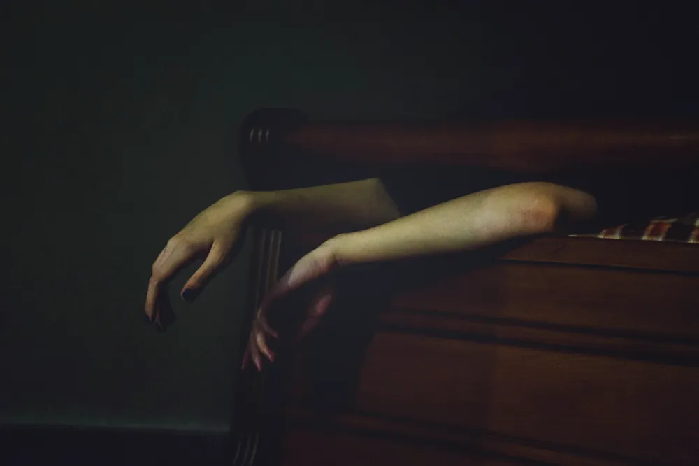 Avant-bras abandonné sur l’accoudoir d’un fauteuil, dans la pénombre, sans visage